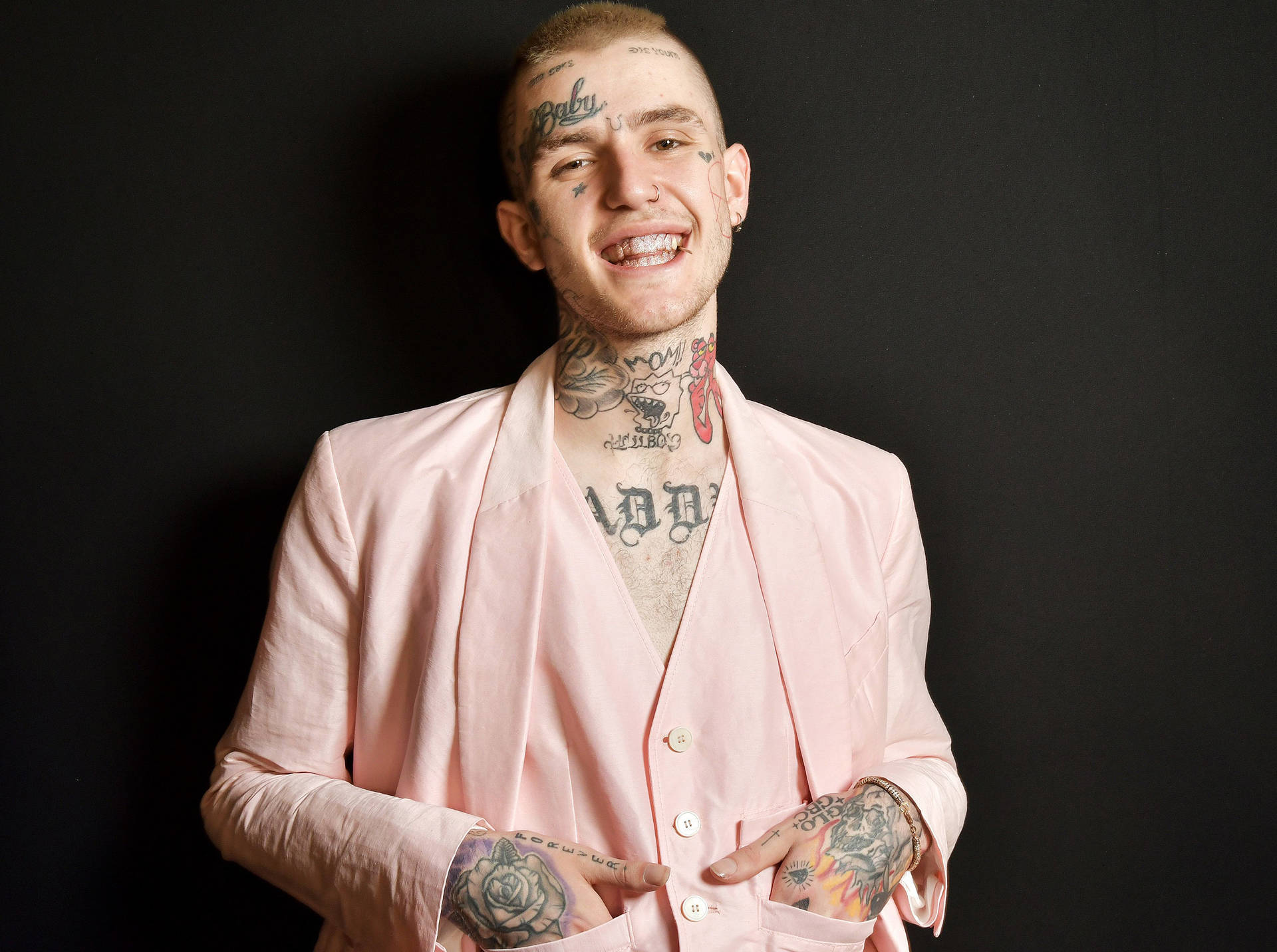 Vibrant Rapper Lil Peep Performing in Pink Suit Background